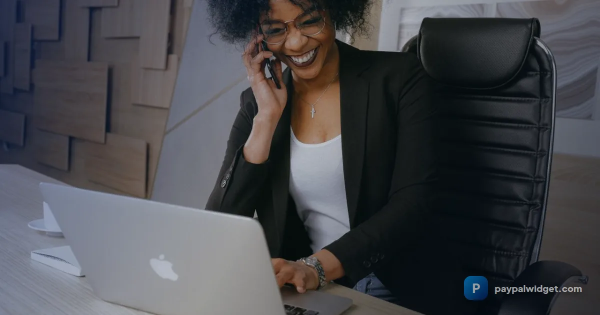 Freelancer tracking their PayPal income on a phone and laptop at a desk